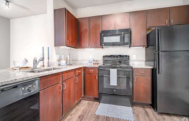 A kitchen with black appliances and wooden cabinets.