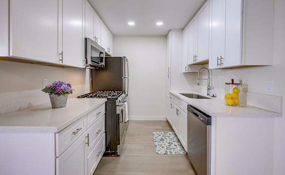 A kitchen with white cabinets and a black refrigerator.