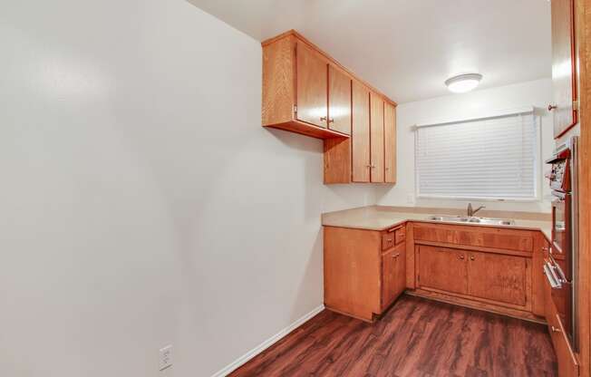 Kitchen with double stainless steel kitchen sink, quartz countertops, stainless steel Microwave oven on the right, wood kitchen cabinets, and wood style floors