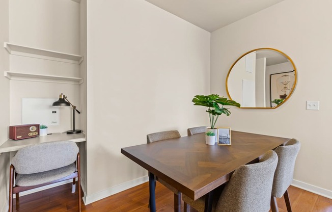 Chic seperate dining room with a patterned wood table next to a small built-in desk with wall shelving and a grey chair at Sylvan Uptown, Denver, CO