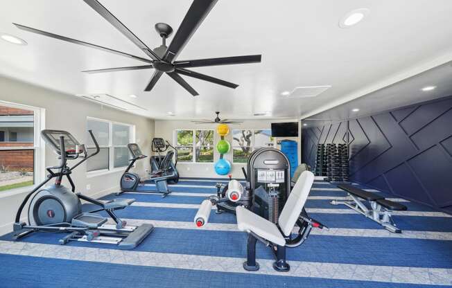 a home gym with exercise equipment and a ceiling fan