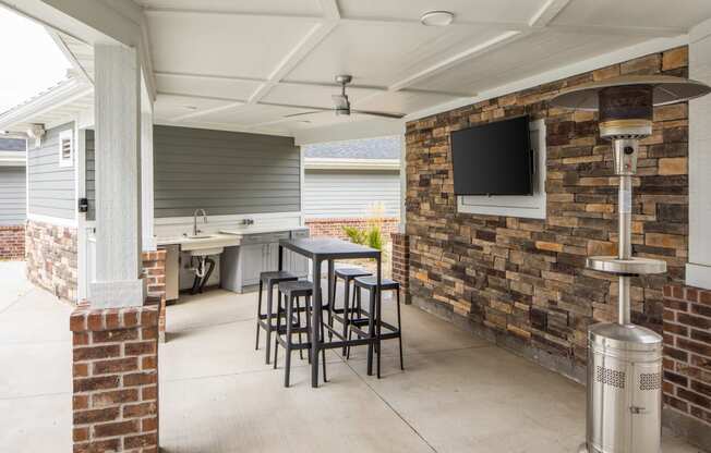 a patio with a table and chairs and a television on the wall