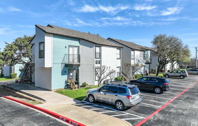 an apartment building with a parking lot and cars in front of it