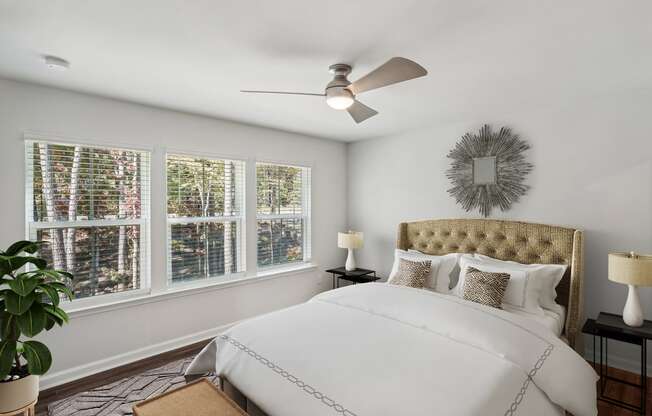 a bedroom with white walls and a ceiling fan