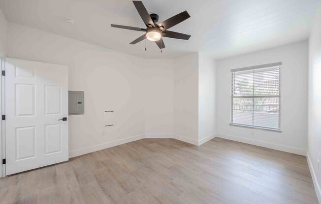 an empty living room with a ceiling fan and a door