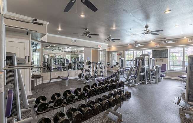 a gym with weights and cardio equipment and ceiling fans