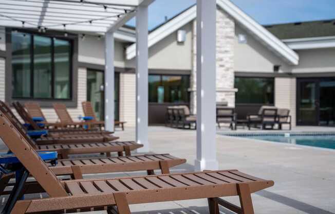 A row of wooden lounge chairs are arranged on a patio.