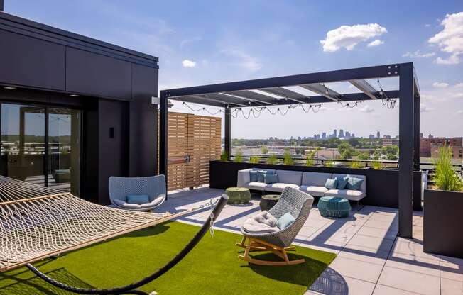 a terrace with lounge chairs and a hammock with a view of the city