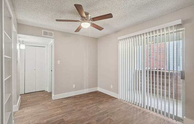 A room with a ceiling fan and a window with blinds.