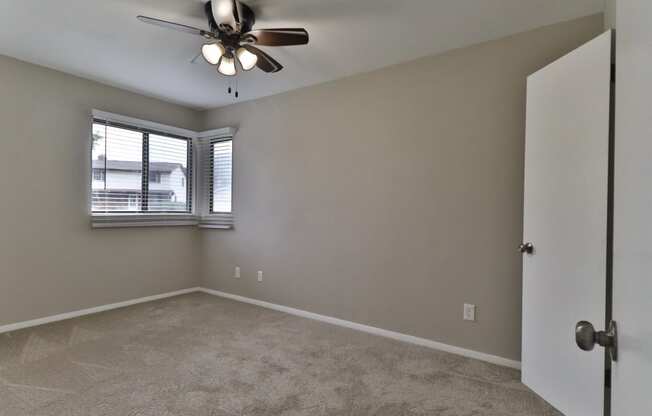 an empty bedroom with a ceiling fan and a window