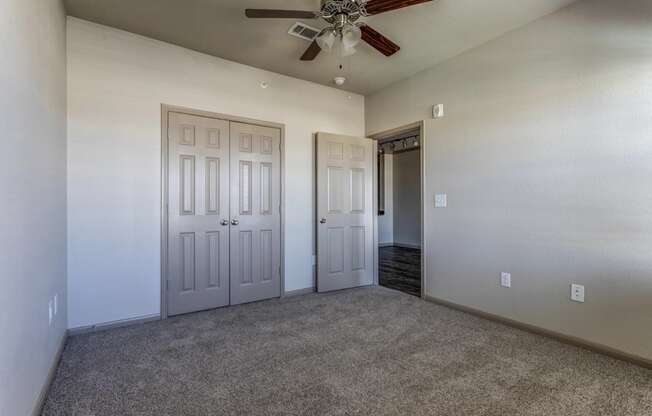 a bedroom with a ceiling fan and closet