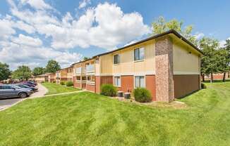 a row of apartment buildings with a green lawn and a parking lot at Lodge of Overland Park Apartments, Overland Park , KS