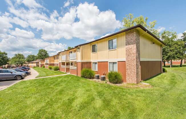 a row of apartment buildings with a green lawn and a parking lot at Lodge of Overland Park Apartments, Overland Park , KS