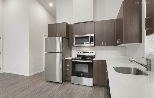 A modern kitchen with a stainless steel refrigerator, microwave, oven, and sink.
