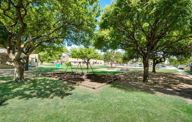 a playground with trees and a swing in a park