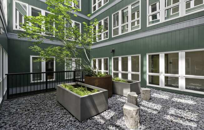 an outdoor courtyard with large concrete planters and stools  t Sedona Apartments, Seattle, 98115