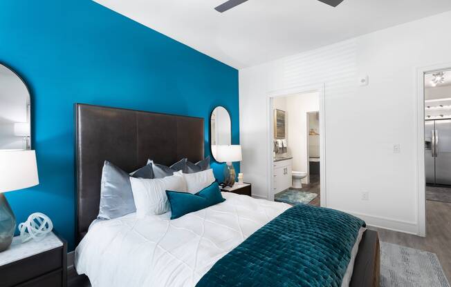 Furnished spacious bedroom with blue accent wall and ceiling fan at Cyan Craig Ranch apartments for rent