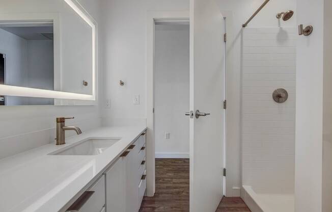 bathroom with fully lit mirror, standing shower and spacious countertops