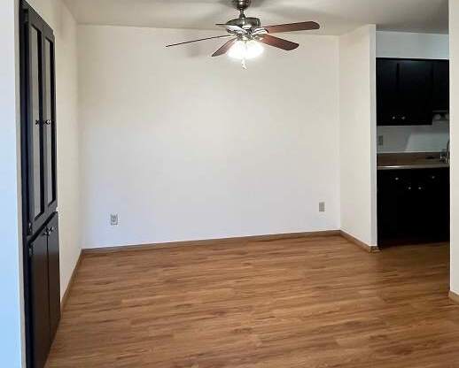 A room with a ceiling fan and wooden flooring.