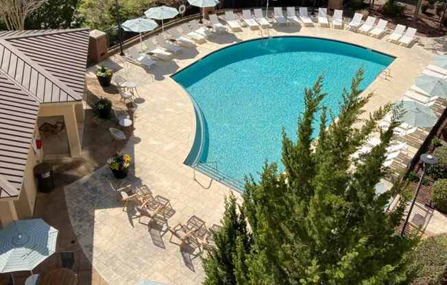 A large swimming pool surrounded by chairs and umbrellas.