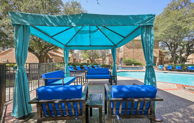 A poolside area with blue chairs and a canopy.