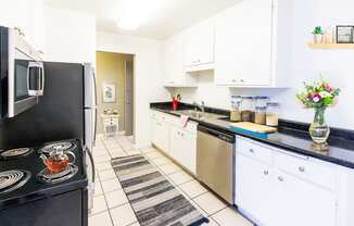 A kitchen with black countertops and white cabinets.