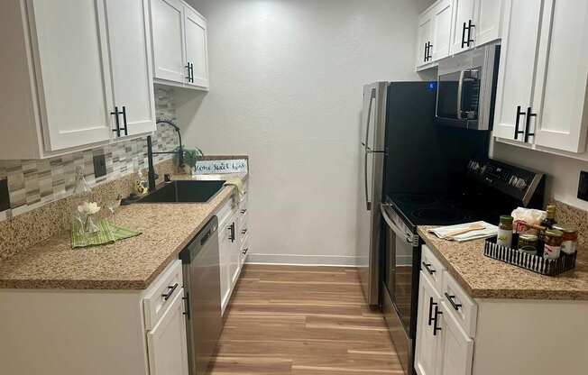A kitchen with white cabinets and a black fridge at Willow Tree Apartments, California, 90505