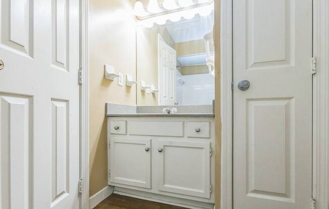 A white bathroom with a vanity and a mirror.