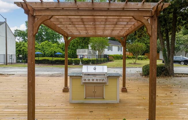 a barbecue grill is under a wooden deck with a pergola