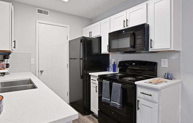 an empty kitchen with black appliances and white cabinets