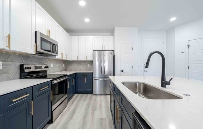 a kitchen with blue and white cabinets and stainless steel appliances