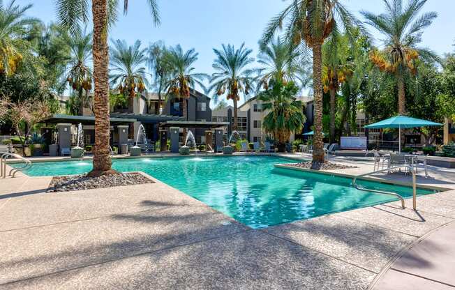 A large swimming pool surrounded by palm trees and lounge chairs.