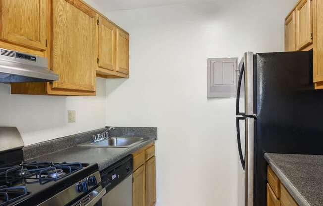 A kitchen with wooden cabinets and a black refrigerator.