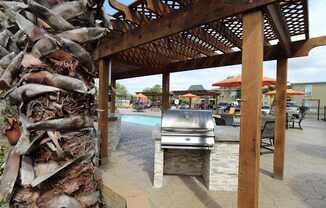 A wooden pergola with a grill underneath it at Willow Creek Apartments, Houston, Texas