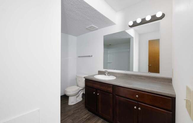 A bathroom with a toilet, sink, and mirror.
