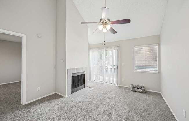 A spacious living room with a fireplace and a ceiling fan.