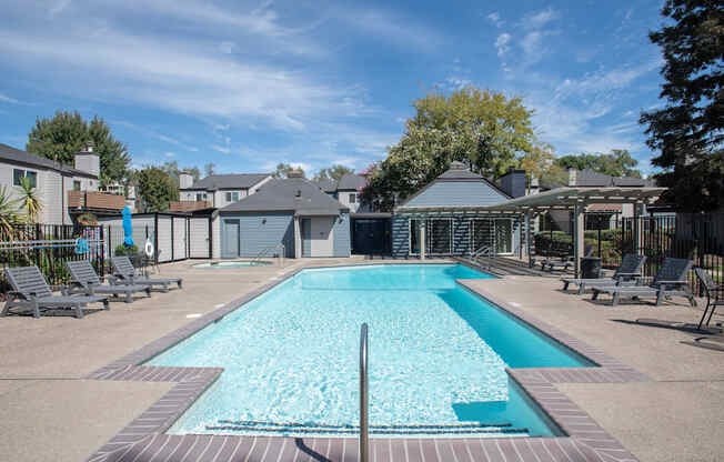 A swimming pool surrounded by lounge chairs and trees at Sierra Glen Apartments, California, 95621
