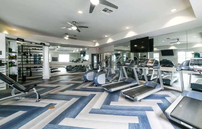 A gym with treadmills, elliptical machines, and other exercise equipment.