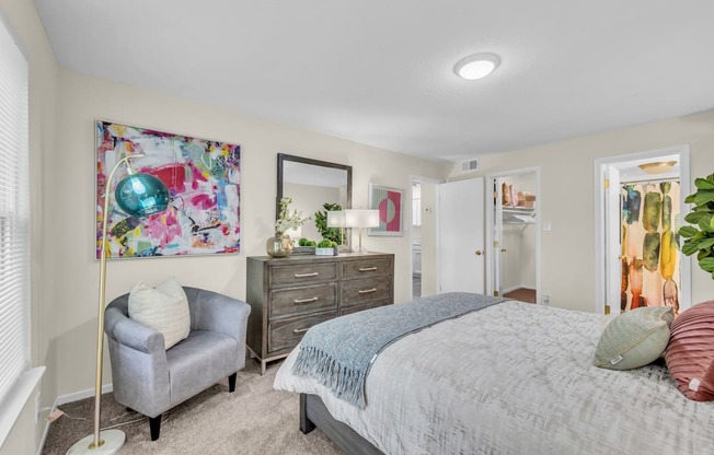 A bedroom with a bed, dresser, and chair.