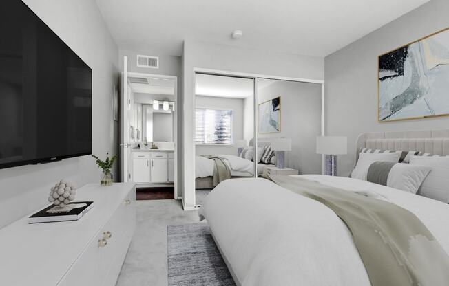 a white bedroom with a large bed and a tv