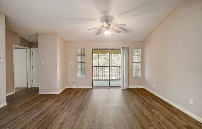 an empty living room with a ceiling fan and a window