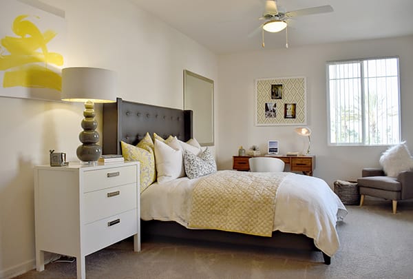 A bedroom with a bed, nightstand, and a ceiling fan.