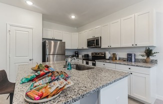 Boatman Hammock Townhomes in Lake Worth, FL photo of a kitchen with white cabinets and granite counter tops and a sink