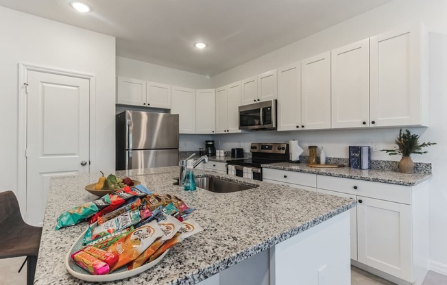 Boatman Hammock Townhomes in Lake Worth, FL photo of a kitchen with white cabinets and granite counter tops and a sink