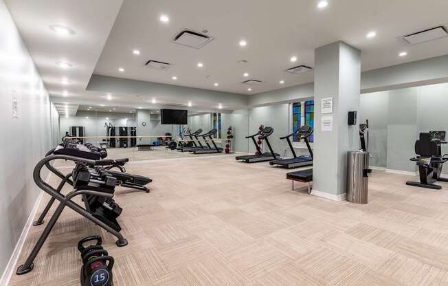 A gym with a variety of exercise equipment including treadmills, stationary bikes, and weight machines.