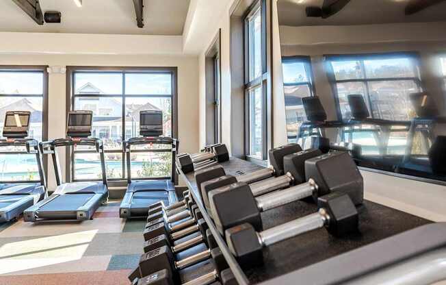 A gym with treadmills, dumbbells and exercise equipment.
