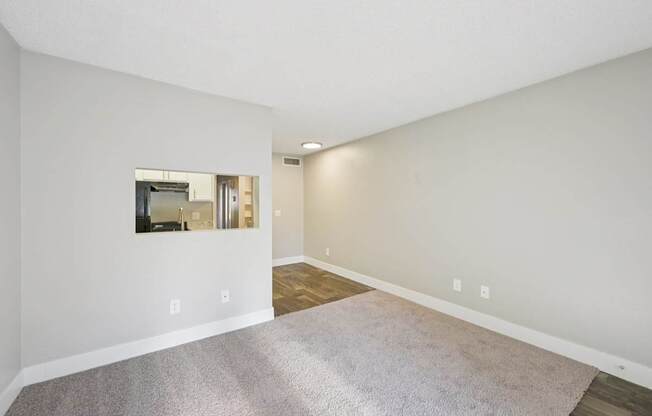 Model living room with a gray carpet and a mirror on the wall.
