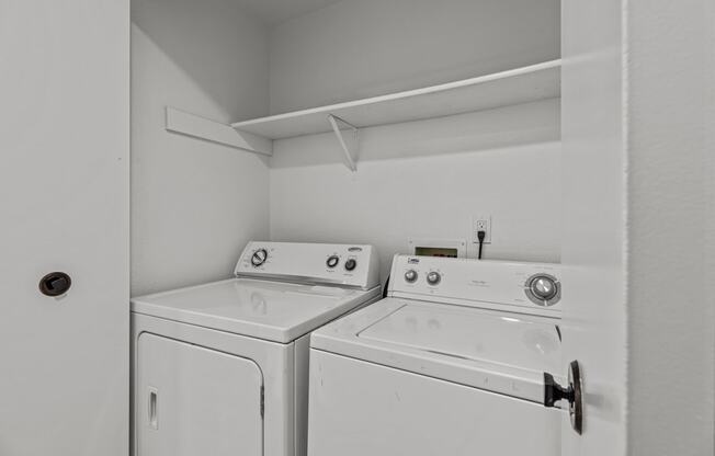 an empty laundry room with two washes and a dryer