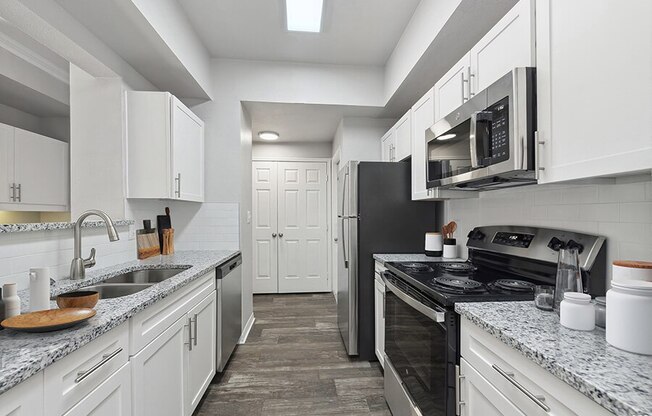 Model Kitchen with White Cabinets and Wood-Style Flooring at Chapel Hill Apartments in Lewisville, TX.