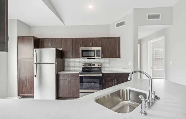 Upgraded kitchens with pull-down faucet, sleek wood cabinetry, and quartz countertops.